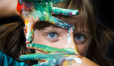 child with paint on her hands painting a portrait